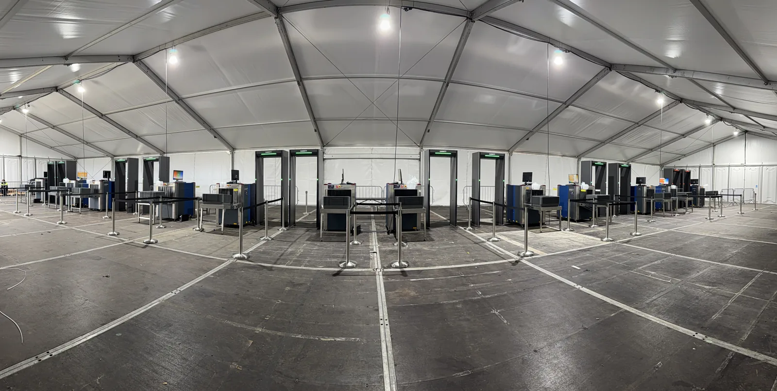 A large temporary screening hall at the Amgen Irish Open with rows of Garrett walk-through metal detectors and Smiths Detection X-ray machines